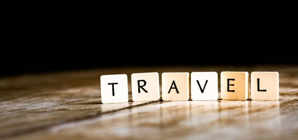 Travel word made of tiles on dark wooden background  - Photo, Image