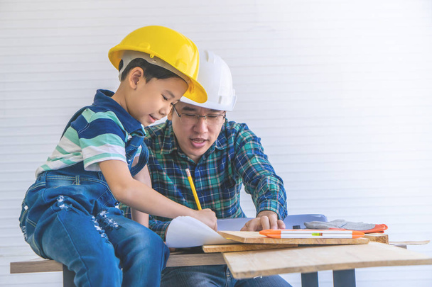 Padre Constructor está enseñando a su hijo a leer el plan de construcción
 - Foto, Imagen