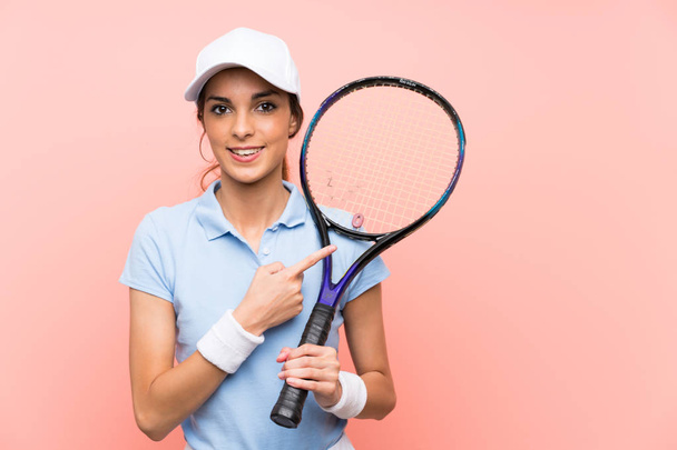 Nuori tennispelaaja nainen yli eristetty vaaleanpunainen seinä osoittaa sivulle esittää tuotteen
 - Valokuva, kuva