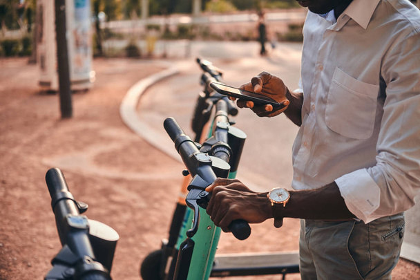 Man is paying for electro scooter using his mobile phone - Photo, Image
