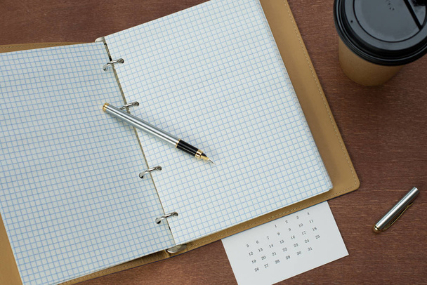 Calendar planner with fountain pen and hot coffee on wood table.office tool. - Foto, Bild