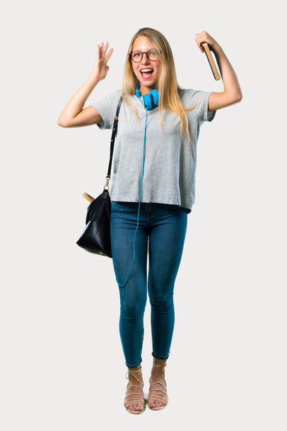 Full body of Student girl with glasses with surprise and shocked facial expression. Gaping because can not believe what is happening on grey background - Fotó, kép
