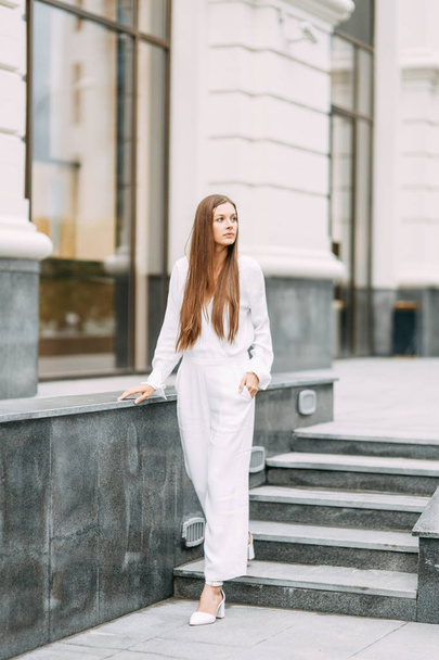 bright photo shoot on the background of the modern city. stylish blogger girl in overalls.  - Valokuva, kuva