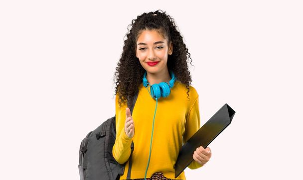Adolescente estudante menina com cabelos cacheados apertando as mãos para fechar um bom negócio em fundo cinza
 - Foto, Imagem