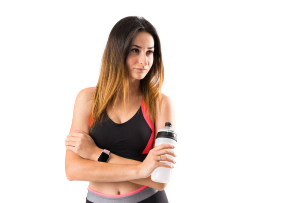 Young sport woman over isolated background with a bottle of wate - Photo, Image