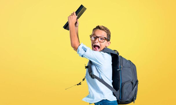 Studentka s batohu a sklenicemi, které drží knížku a skáčou na žlutém pozadí - Fotografie, Obrázek