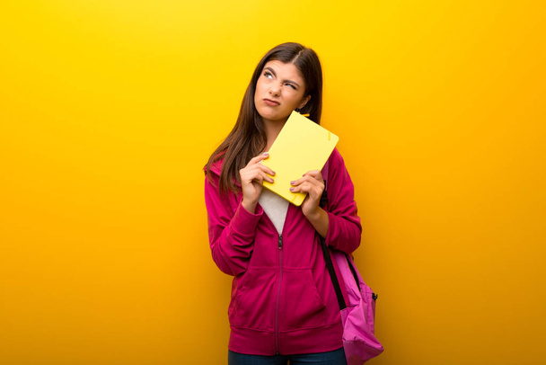Teenager student girl on vibrant yellow background makes funny and crazy face emotion - Photo, image