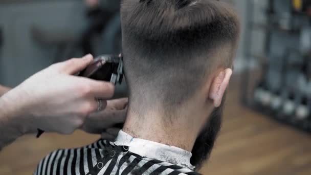 Close-up view on males hairstyling in a barber shop with professional trimmer. Mans haircutting at hair salon with electric clipper. Grooming the hair. - Séquence, vidéo