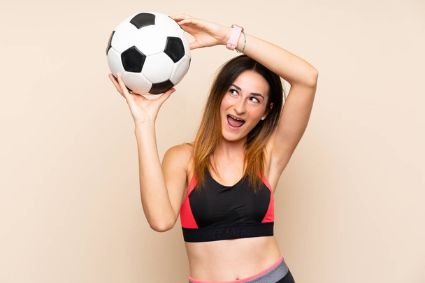 Νεαρό άθλημα γυναίκα πάνω από το απομονωμένο φόντο κρατώντας μια μπάλα ποδοσφαίρου - Φωτογραφία, εικόνα