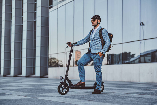 Man is driving his new electro scooter near big glass building - 写真・画像