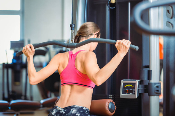Donna in forma che esercita lat push down per i muscoli della schiena in un moderno fitness club
 - Foto, immagini