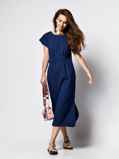 Slender curly female model in a blue urban dress in full growth. Lovely girl in romantic clothes goes on a date, to the office, to a meeting. Urban fashion - Foto, Imagen