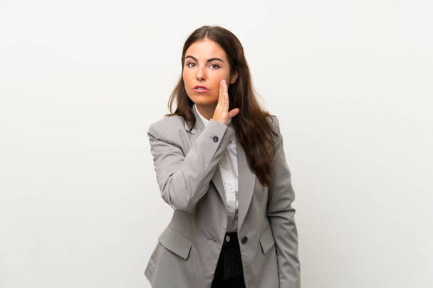 Jonge zakenvrouw over geïsoleerde witte achtergrond fluisteren iets - Foto, afbeelding