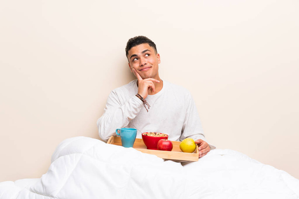 Young man having breakfast in bed thinking an idea - Foto, imagen