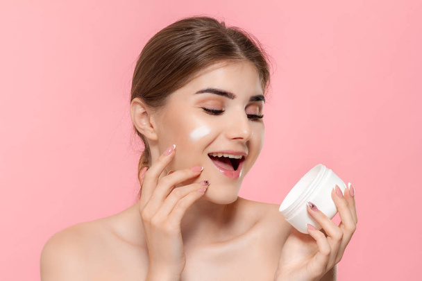 Beautiful model applyes moisturizing cosmetic product to skin holding white tube of a hyaluronic cream.  - Φωτογραφία, εικόνα
