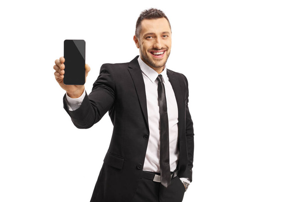 Young man in a suit showing a mobile phone and smiling - Fotoğraf, Görsel