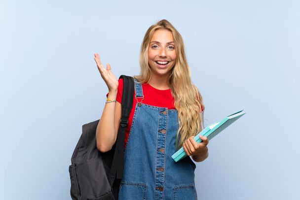 Young blonde student woman over isolated blue wall with surprise facial expression - Photo, Image