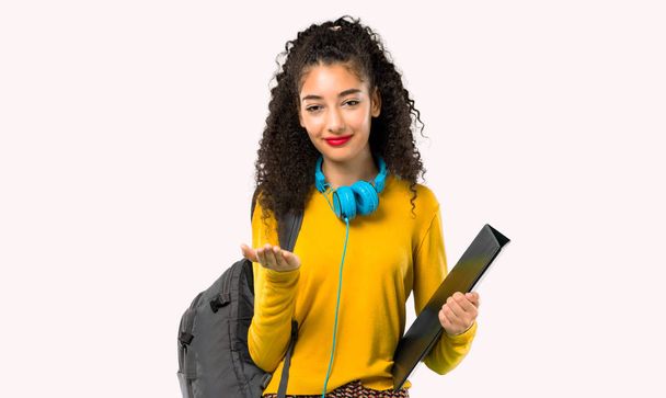 Tiener student meisje met krullend haar houden kopie ruimte denkbeeldig op de Palm om een advertentie in te voegen op een grijze achtergrond - Foto, afbeelding