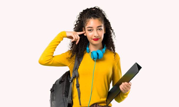 Menina estudante adolescente com cabelo encaracolado cobrindo ambas as orelhas com as mãos. Expressão frustrada sobre fundo cinzento
 - Foto, Imagem