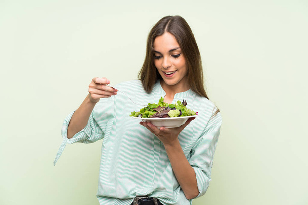 Giovane donna con insalata oltre isolato muro verde
 - Foto, immagini