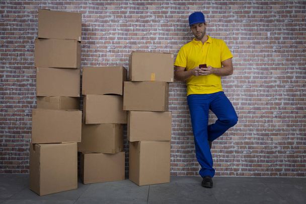 Brazilian mailman using a smartphone in front of a lot of packag - Photo, Image