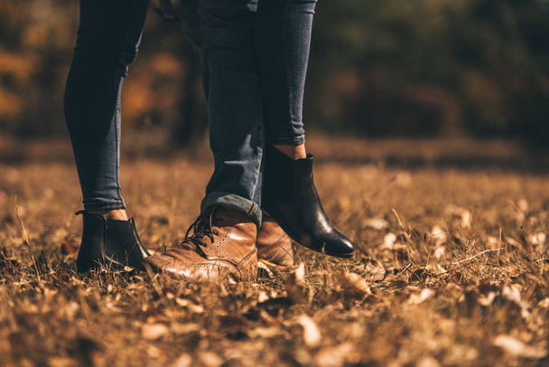 Excelente pareja en jeans está de pie con sus botas en la hierba verde en el bosque
 - Foto, imagen