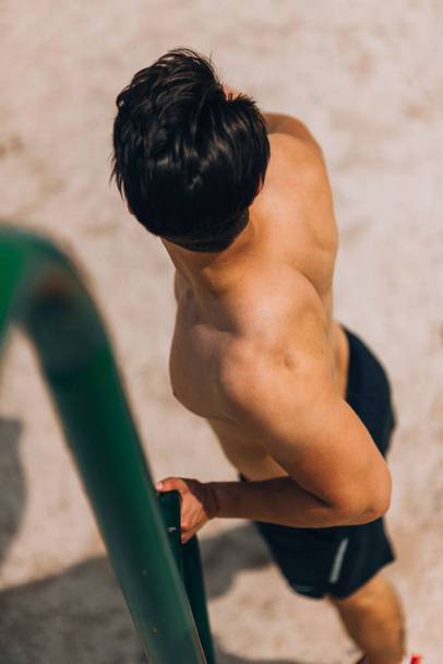 Fit man workout uit armen op dips horizontale staven training triceps en biceps - Foto, afbeelding