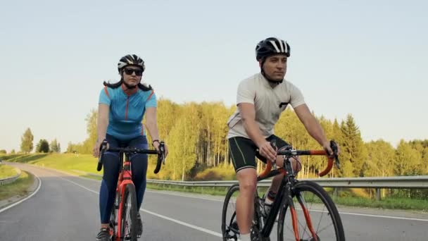 Steadicam schot van fietsen paar berg rijden op fietsweg bij zonsondergang doen hoge - Video