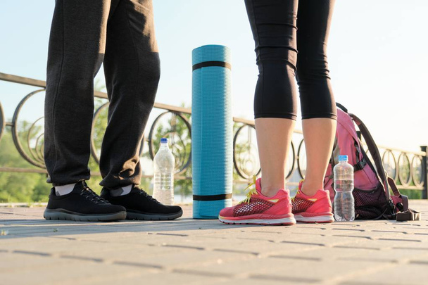 Close-up de pernas de casal em tênis com garrafa de água de tapete de exercício
 - Foto, Imagem