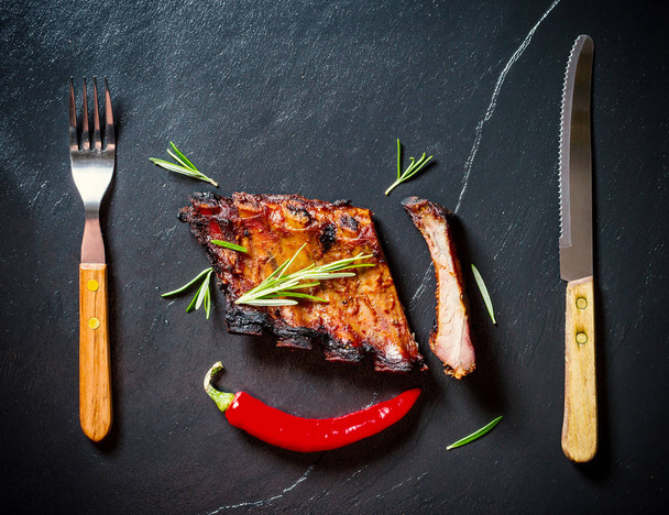 Grilled spareribs on slate plate with cutlery - Foto, Imagen
