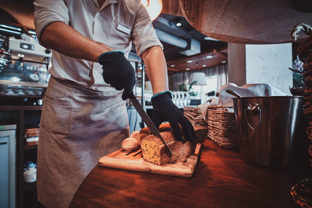 Kitchen worker is slicing bread for lunch - Zdjęcie, obraz