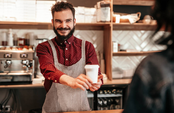 Alegre barista sirviendo café caliente al cliente en la cafetería
 - Foto, Imagen