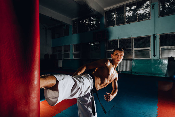Retrato del luchador tailandés muay concentrado practicando patada en el saco de boxeo
 - Foto, imagen