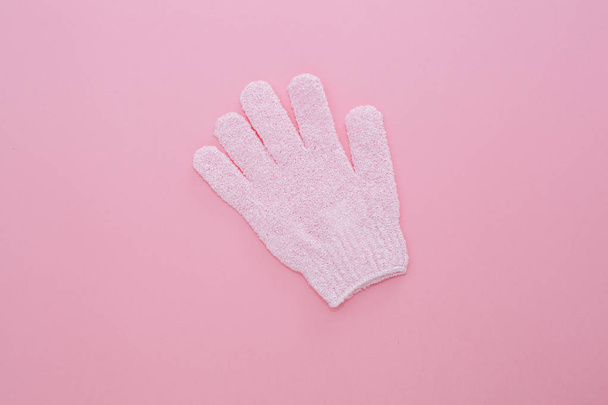 Woman exfoliating massage glove for shower on pink background. - Foto, afbeelding
