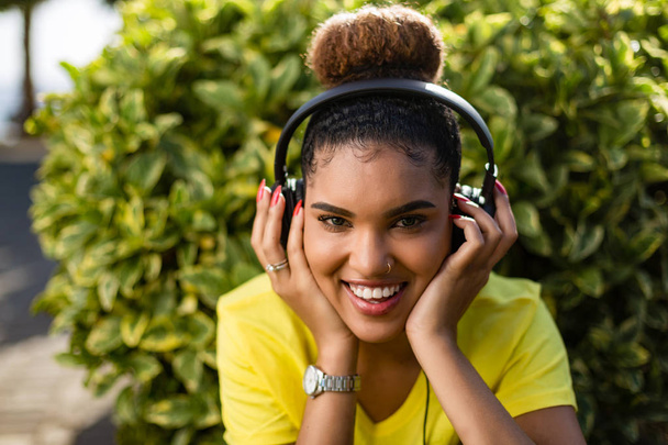Όμορφη νεαρή μαύρη αφρικανική Αμερικανίδα γυναίκα ακούγοντας μουσική εξυπνάδα - Φωτογραφία, εικόνα