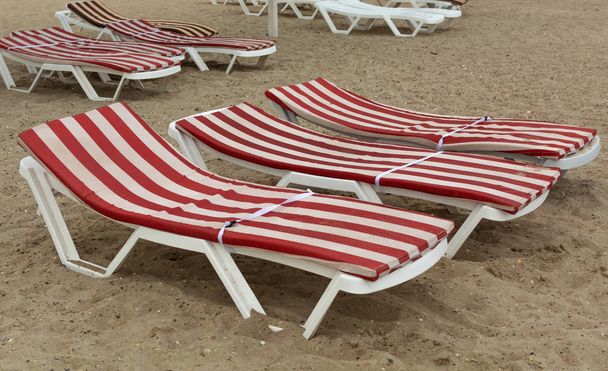 Пластиковые пляжные кровати с полосатыми матрасами
 - Фото, изображение