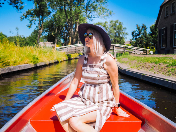Vack of girl with blond hair and blue hat sit on a boat ride at  - Foto, immagini
