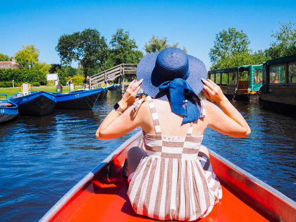 Takaisin näkymä tyttö vaaleat hiukset ja sininen hattu istua veneessä eroon
 - Valokuva, kuva