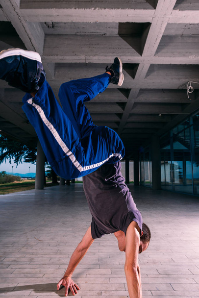 Young parkour man perform handstand at urban place - 写真・画像