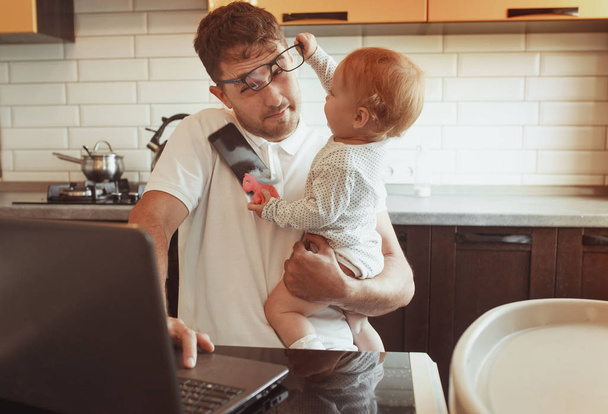 Multitasking Father Working From Home On Laptop With Baby daught - Foto, afbeelding
