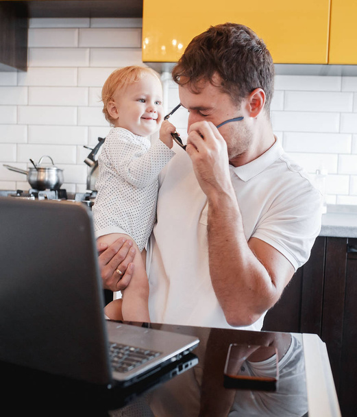 Perhe-isä työskentelee kannettavan tietokoneen kanssa Internetin kautta, puhuva puhelin
 - Valokuva, kuva