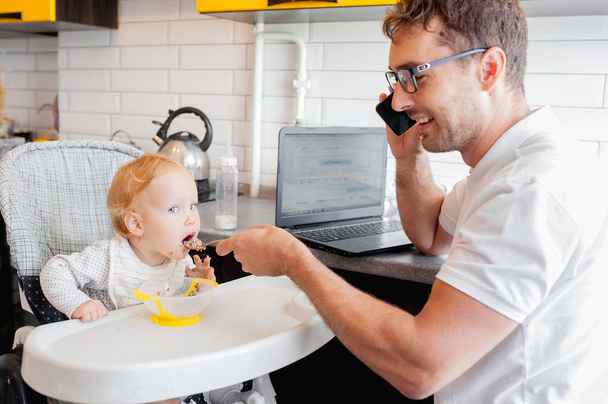 Happy young father working at home and sitting with a baby girl. - Valokuva, kuva
