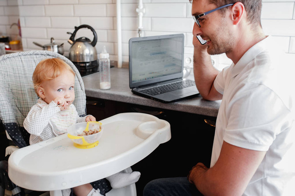 Happy young father working at home and sitting with a baby girl. - 写真・画像