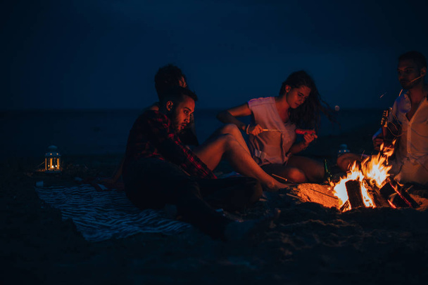 Ξέγνοιαστοι φίλοι κάθονται μαζί το ρομαντικό βράδυ δίπλα στο bea - Φωτογραφία, εικόνα