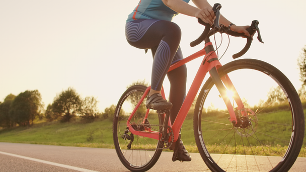 Deux cyclistes un homme et une femme roulent sur l'autoroute sur des vélos de route portant des casques et des vêtements de sport au coucher du soleil au ralenti
. - Séquence, vidéo