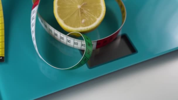 A multi-colored centimeter and a half of fresh lemon are on the aquamarine floor scales. Healthy foods and weight management tools - Metraje, vídeo