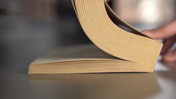 Man leafs through an old book turning over pages on a gray surface. Slow motion. Knowledge Concept - Filmmaterial, Video