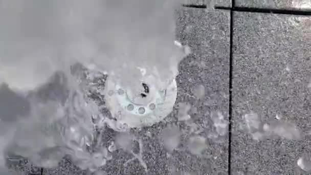 Allegro flusso d'acqua che sale e cade su un foro fontana in una lastra di pavimentazione
 - Filmati, video