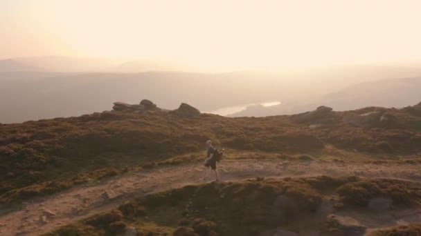 Aerial - Following a young male climbing along a stunning hillside at sunset - Footage, Video