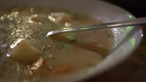 Talíř polévky s kovovou lžičkou v tmavé kuchyni uvnitř - Záběry, video